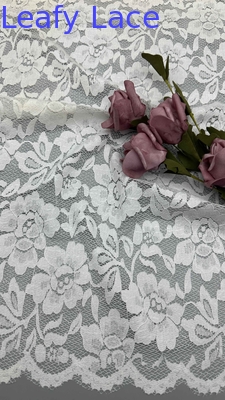 Volle breedte strektante kantstof in wit, versierd met delicate bloemenpatronen en luxueuze kanten.